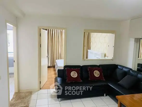 Cozy living room with black leather sofa and view into bedroom