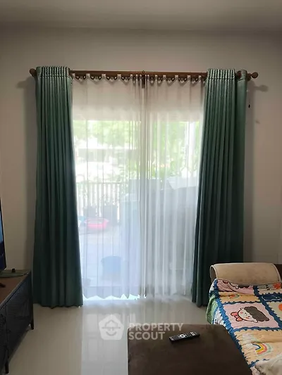 Cozy living room with elegant curtains and plush seating, offering a serene view of the outdoors.