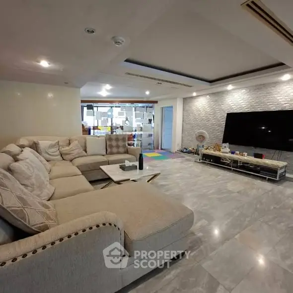 Spacious modern living room with elegant sectional sofa and large TV, perfect for family gatherings.