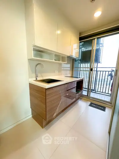 Modern kitchen with sleek cabinetry and balcony access in a high-rise apartment.