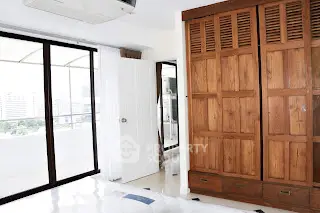 Spacious bedroom with wooden wardrobe and balcony access in modern apartment.