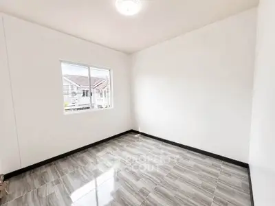 Bright empty room with tiled flooring and large window in modern home