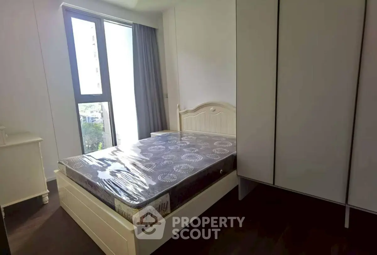 Bright bedroom with large window and modern furnishings in a stylish apartment.