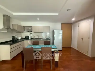 Modern kitchen with dining area, featuring sleek cabinets and stainless steel appliances.
