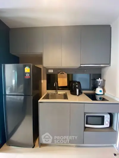 Modern compact kitchen with sleek cabinets, stainless steel fridge, and built-in appliances.
