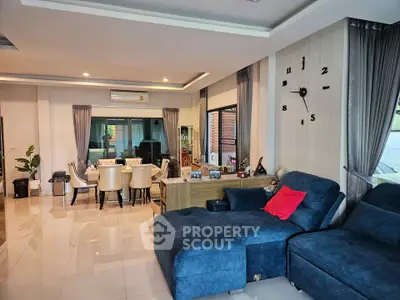 Spacious living room with modern decor and dining area, featuring plush blue seating and elegant dining set.