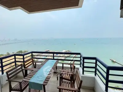 Stunning ocean view from spacious balcony with wooden furniture, perfect for relaxation and entertaining.