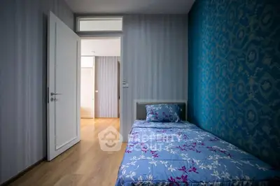 Cozy bedroom with floral bedding and stylish wallpaper, perfect for a peaceful retreat.