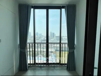 Bright room with large window offering stunning cityscape view, perfect for urban living.