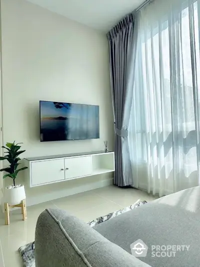 Modern living room with wall-mounted TV and large window with curtains