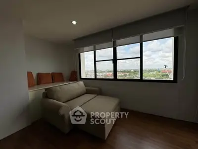 Cozy living room with a stunning city view through large windows, featuring a comfortable sofa and modern decor.