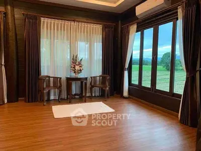 Spacious living room with large windows offering stunning countryside views, elegant wooden flooring, and cozy seating area.