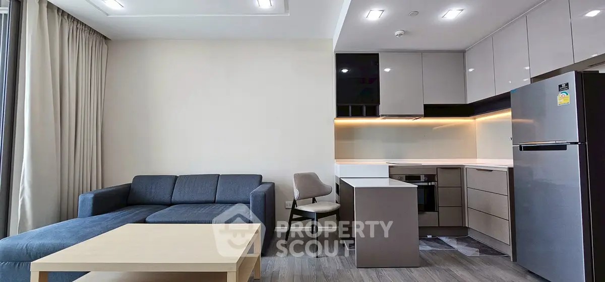 Modern open-layout living room with sleek kitchen and cozy seating area.