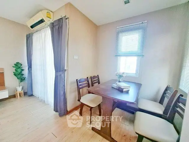 Cozy dining area with wooden table and chairs, natural light from window, and air conditioning.