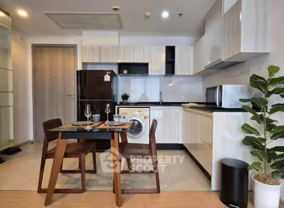 Modern kitchen with dining area, featuring sleek cabinets, washing machine, and stylish decor.