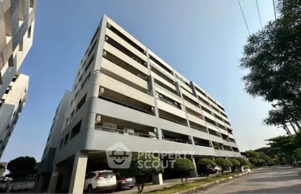 Modern multi-story apartment building with parking and landscaped surroundings.