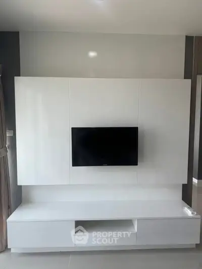 Modern living room with sleek white TV unit and mounted flat-screen TV.