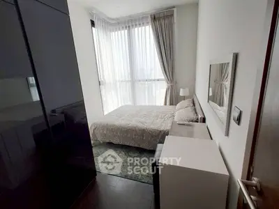 Modern bedroom with large window and stylish decor in a high-rise apartment.
