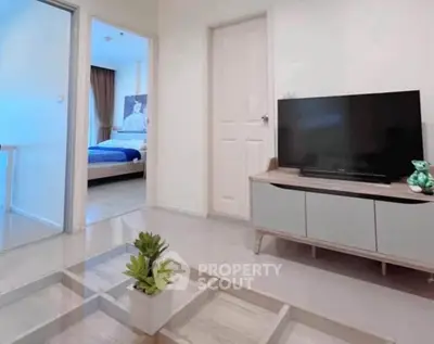 Modern living room with sleek TV stand and view into cozy bedroom