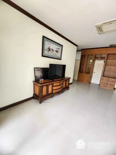 Spacious living room with elegant wooden furniture and mounted TV, featuring a bright and airy atmosphere.