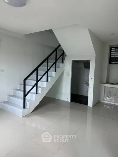Modern interior with sleek staircase and tiled flooring, leading to a compact bathroom.