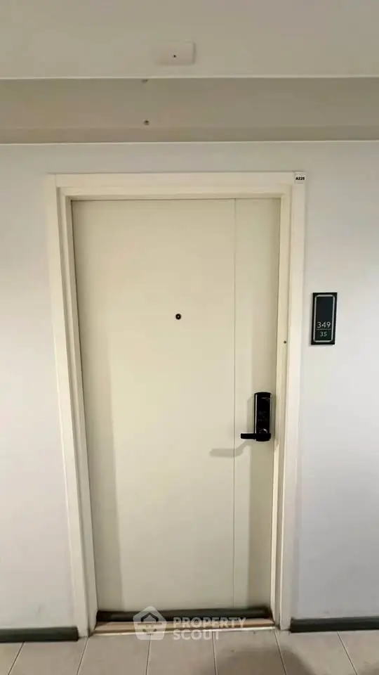 Modern apartment entrance with sleek door and digital lock in a well-maintained hallway.