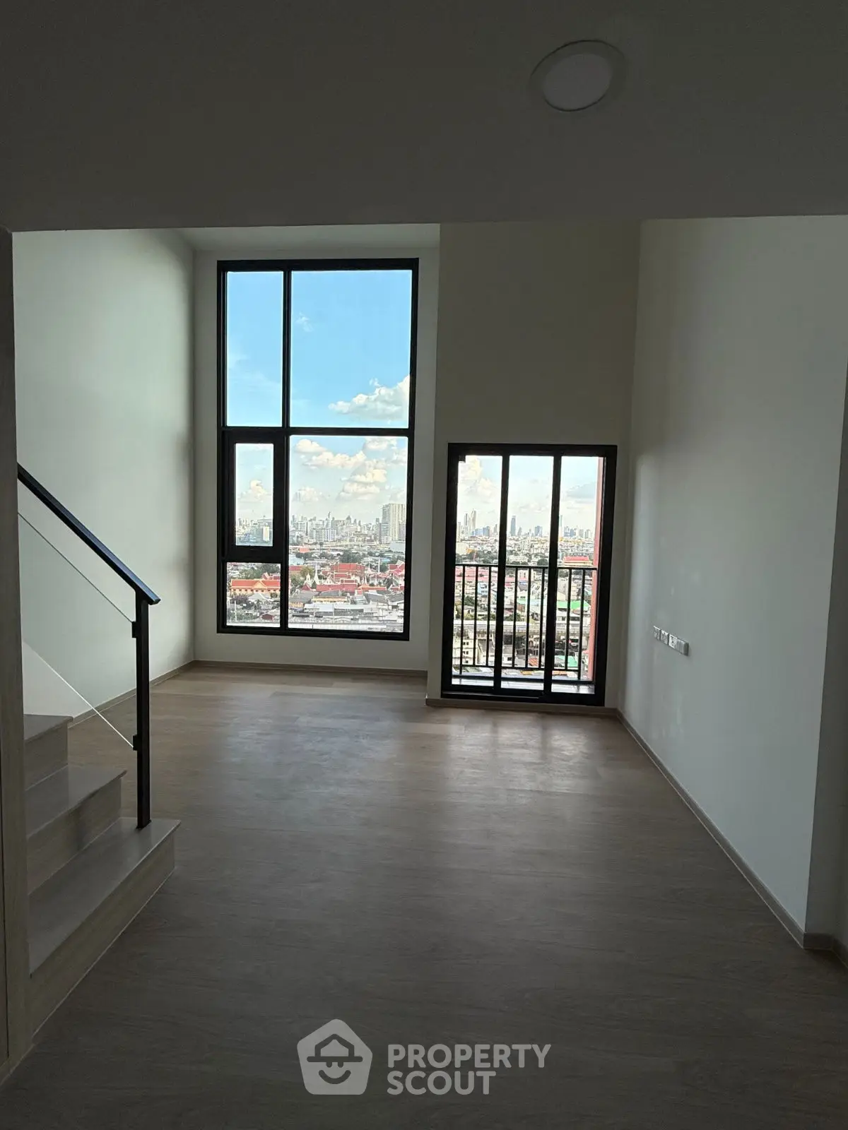 Spacious living room with large windows offering stunning city views.