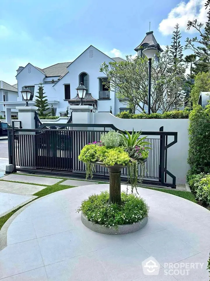 Elegant white villa with lush garden and modern gate in a serene neighborhood.