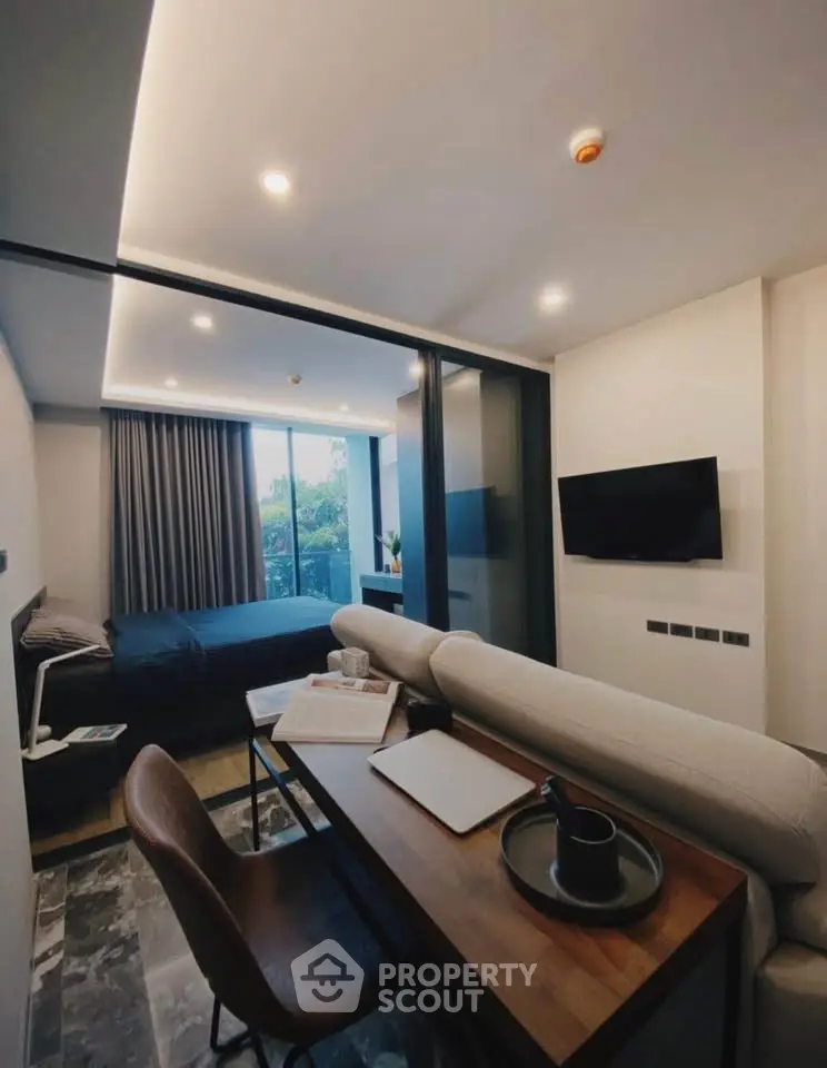 Modern studio apartment with sleek design, featuring a cozy living area, workspace, and large windows for natural light.