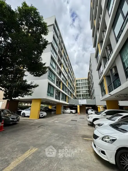 Modern apartment building with parking area and cars, showcasing urban living.