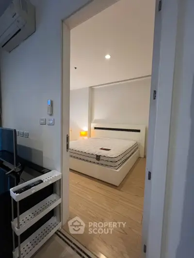 Cozy bedroom with modern decor and wooden flooring, featuring a comfortable bed and ambient lighting.