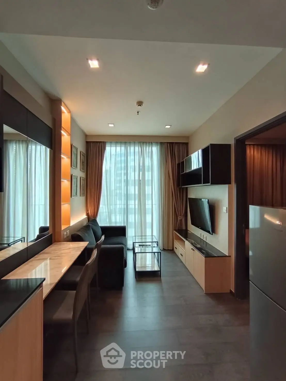 Modern living room with sleek furniture and large window offering natural light.