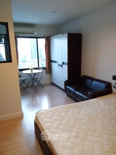 Cozy bedroom with city view, featuring a comfortable bed, wardrobe, and a small seating area by the window.