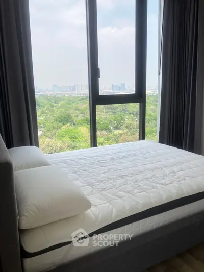 Modern bedroom with large window offering stunning city and park view.