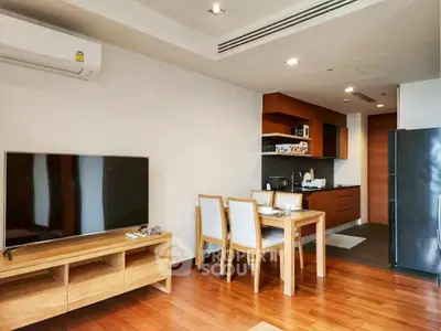 Modern living room with open kitchen, wooden flooring, and sleek furniture