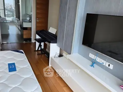 Modern bedroom with wooden flooring, wall-mounted TV, and sleek furniture in a high-rise apartment.