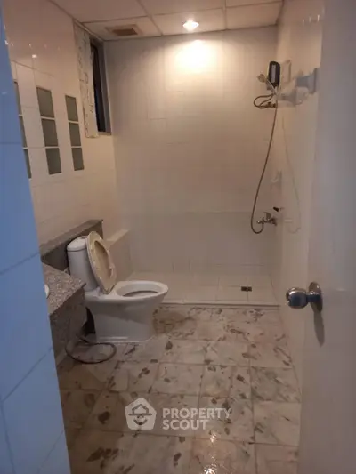 Spacious bathroom with modern fixtures and tiled flooring in a real estate property.