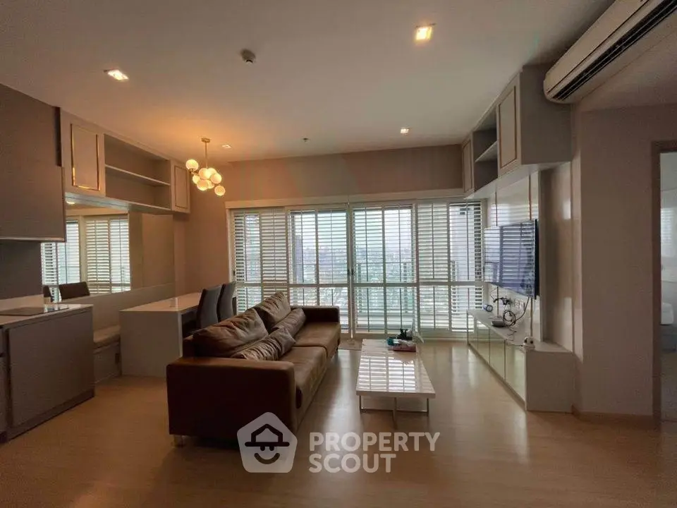 Spacious modern living room with large windows and city view, featuring cozy sofa and stylish decor.
