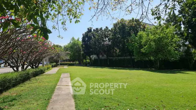 Spacious green garden with lush trees and clear blue sky, perfect for relaxation.