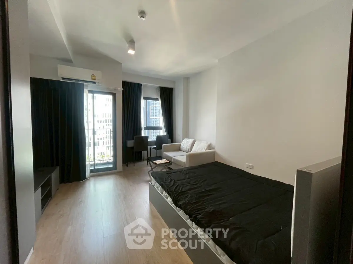 Modern studio apartment with sleek design and city view, featuring a cozy living area and natural light.