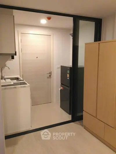 Modern compact kitchen with sleek cabinetry and appliances in a stylish apartment.