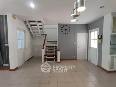 Spacious modern living room with stylish staircase and wall clock, perfect for family gatherings.