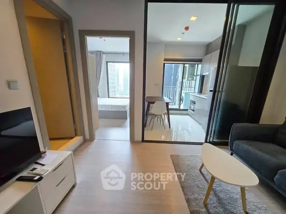 Modern apartment interior with open layout, featuring living room, kitchen, and bedroom view.