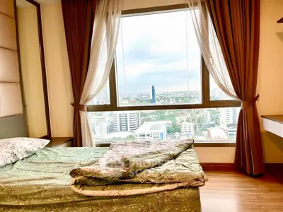 Spacious bedroom with stunning city view from large window, featuring elegant curtains and cozy bedding.
