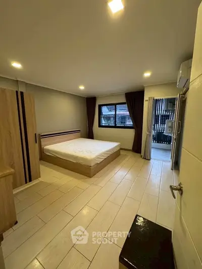 Spacious bedroom with modern design and large window offering natural light.