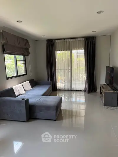 Spacious living room with modern gray sofa and large windows offering natural light.