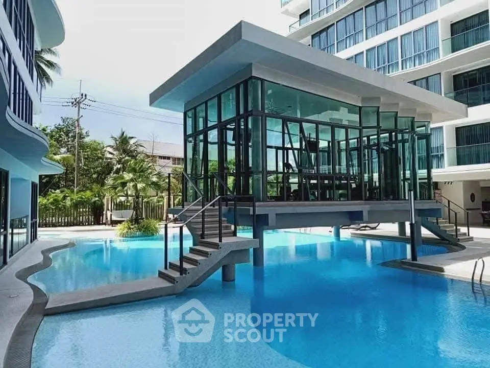 Luxurious modern poolside view with glass-walled gym in upscale residential complex.