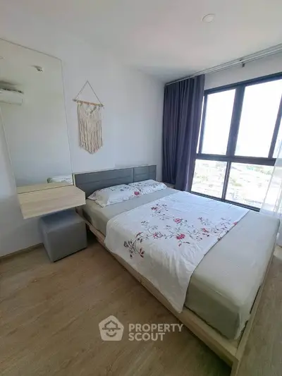 Modern bedroom with large window and stylish decor in a high-rise apartment.