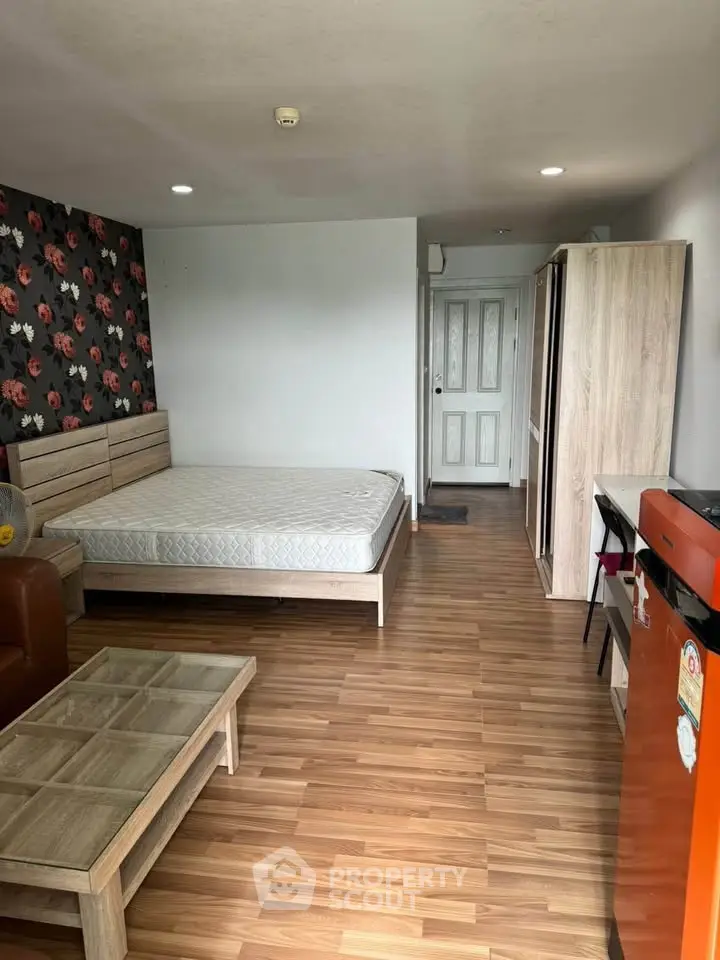 Spacious studio apartment with modern decor and wooden flooring, featuring a cozy bed and stylish furniture.