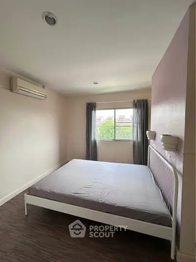 Spacious bedroom with large window and air conditioning, offering a serene view.